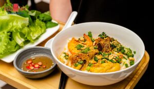 A bowl of Danang Quang Noodles with turmeric broth and fresh herbs